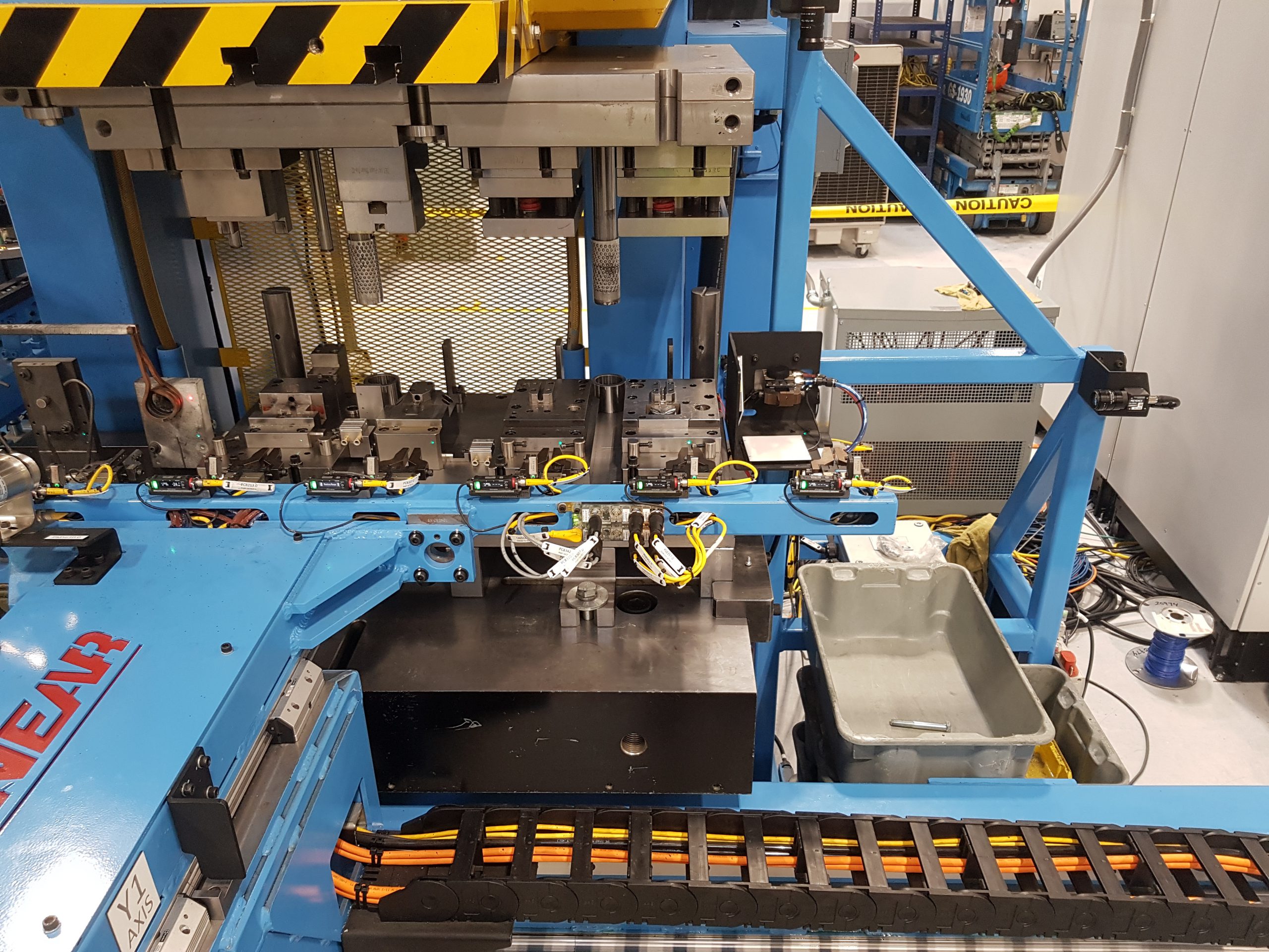 An image of a blue, forging machine with a custom Linear Automation transfer system.